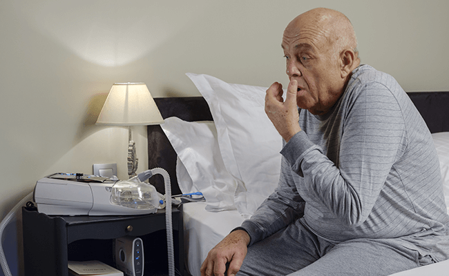COPD-zittende-hoestende-man-non-invasieve-beademing-mobiel